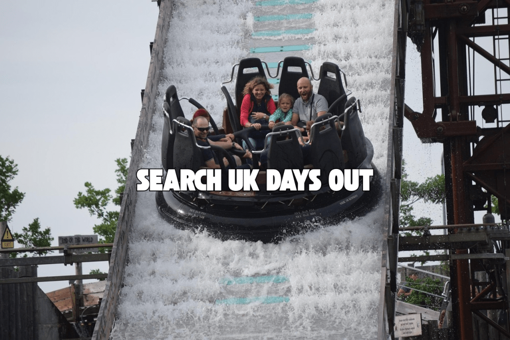 A group of people enjoying a water ride at an amusement park, descending a steep slide with splashes of water.