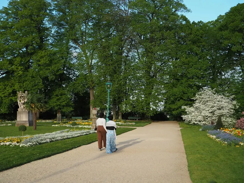 A park path lined with trees and flowers