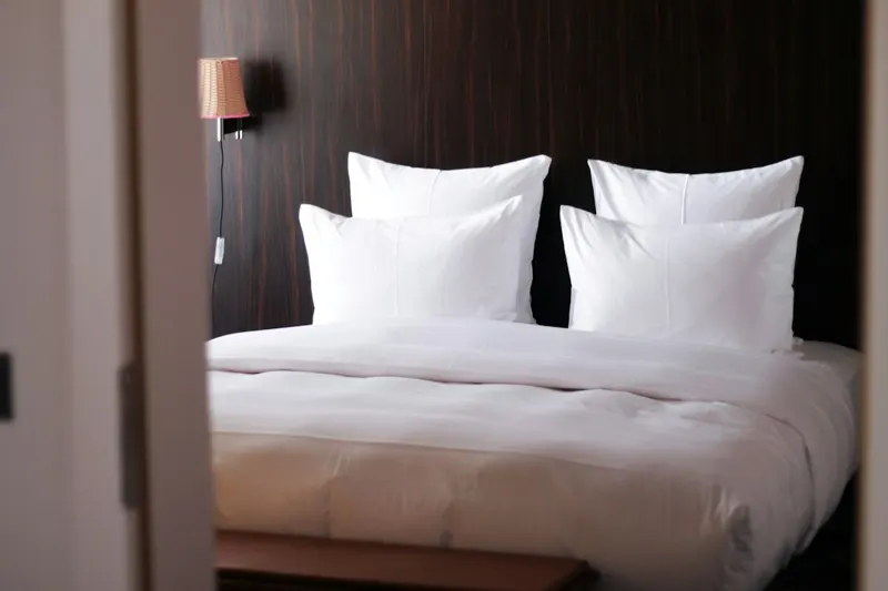 A hotel bedroom with white bed linen